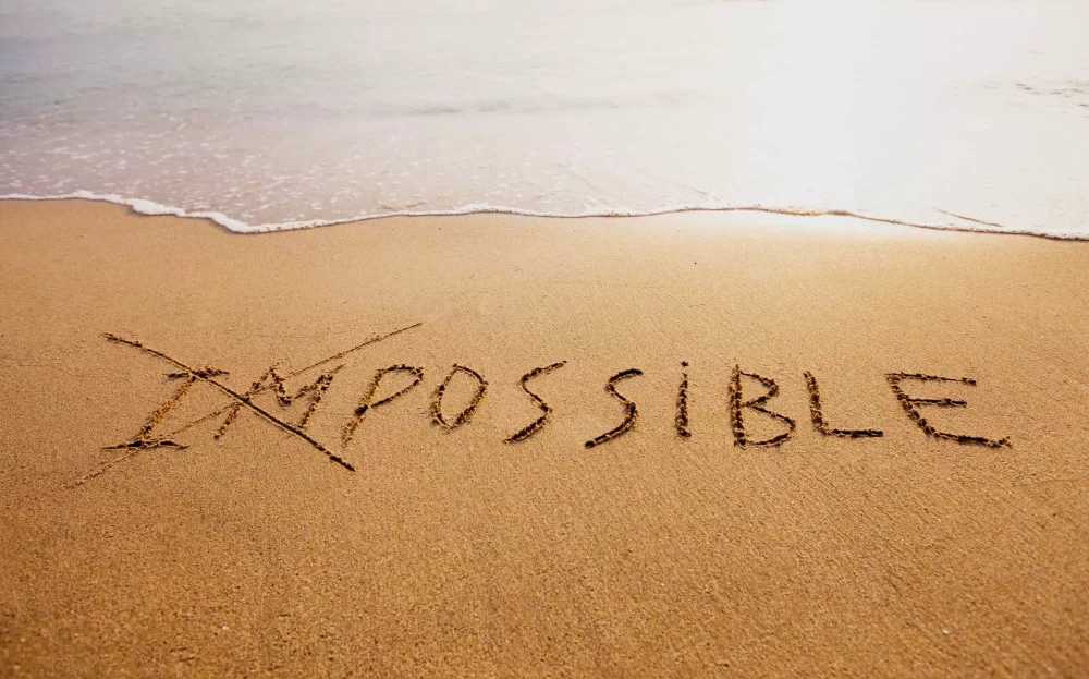 Une image de bord de mer avec sur la plage le mot impossilble ou le im est barré pour un bilan de compétences